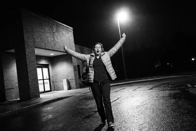 A nurse stretching her arms wide outside the hospital at night
